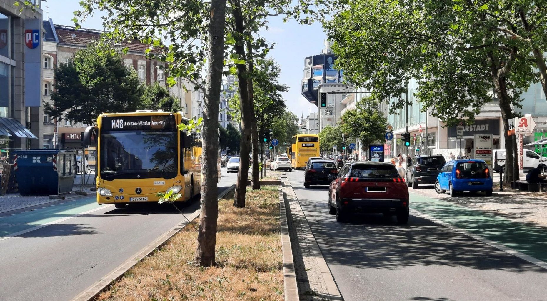 Auf der Schloßstraße in Berlin-Steglitz fahren Busse der BVG und Autos. Im Hintergrund ist eine grüne Ampel zu sehen.