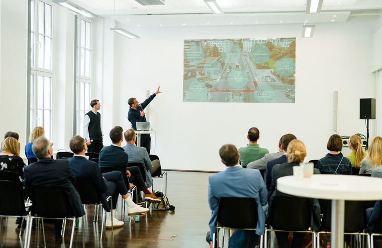 Workshop-Situation: Zwei Redner stehen vorne und erklären dem Publikum die Präsentationsfolie 